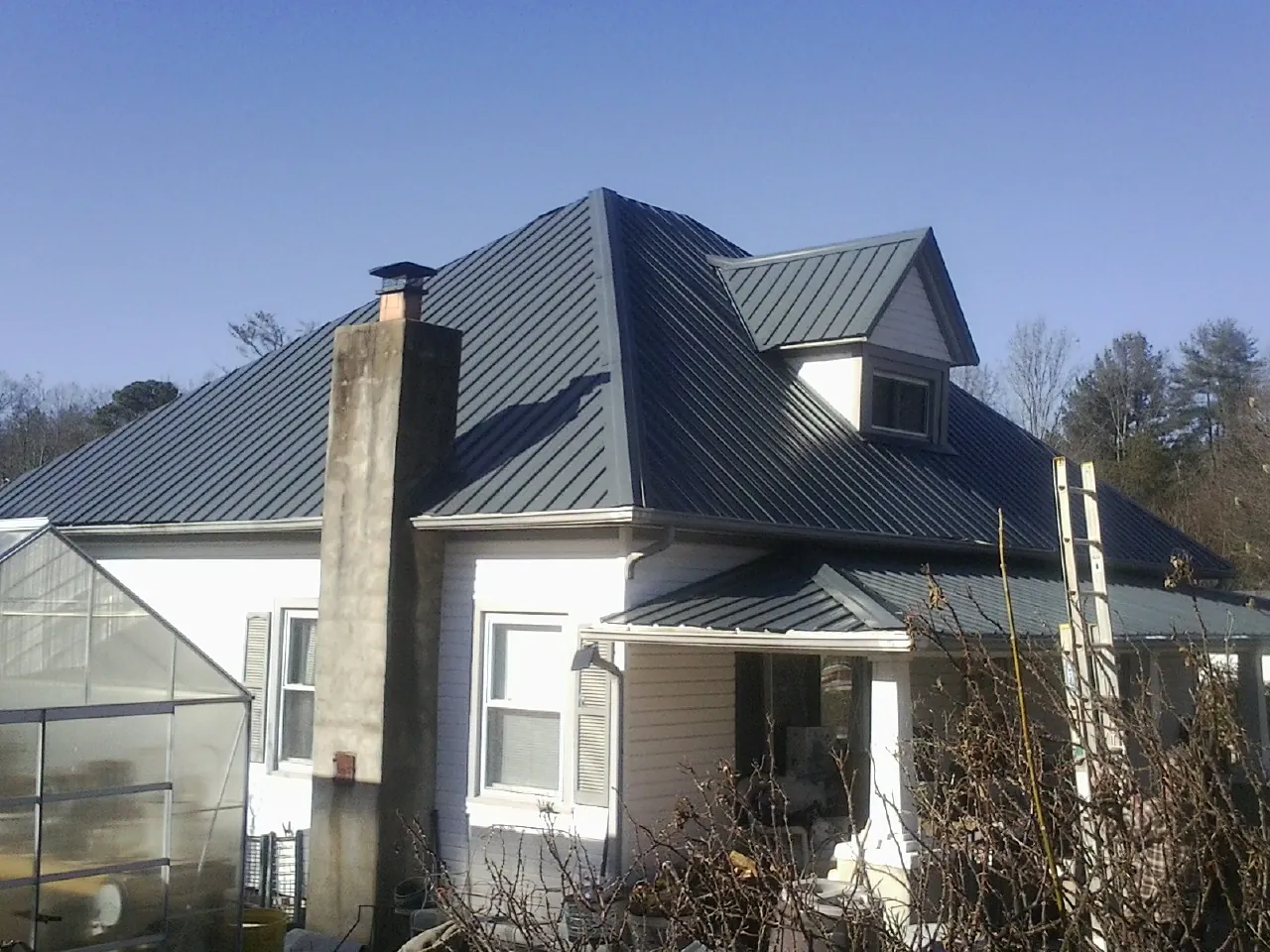Dark blue standing seam metal roof on a white farmhouse with dormer — Slate & Tile Roof Repair by Roofing Brothers in Circleville